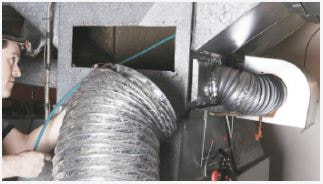 Man looking inside duct system while pushing and guiding brush tool inside system